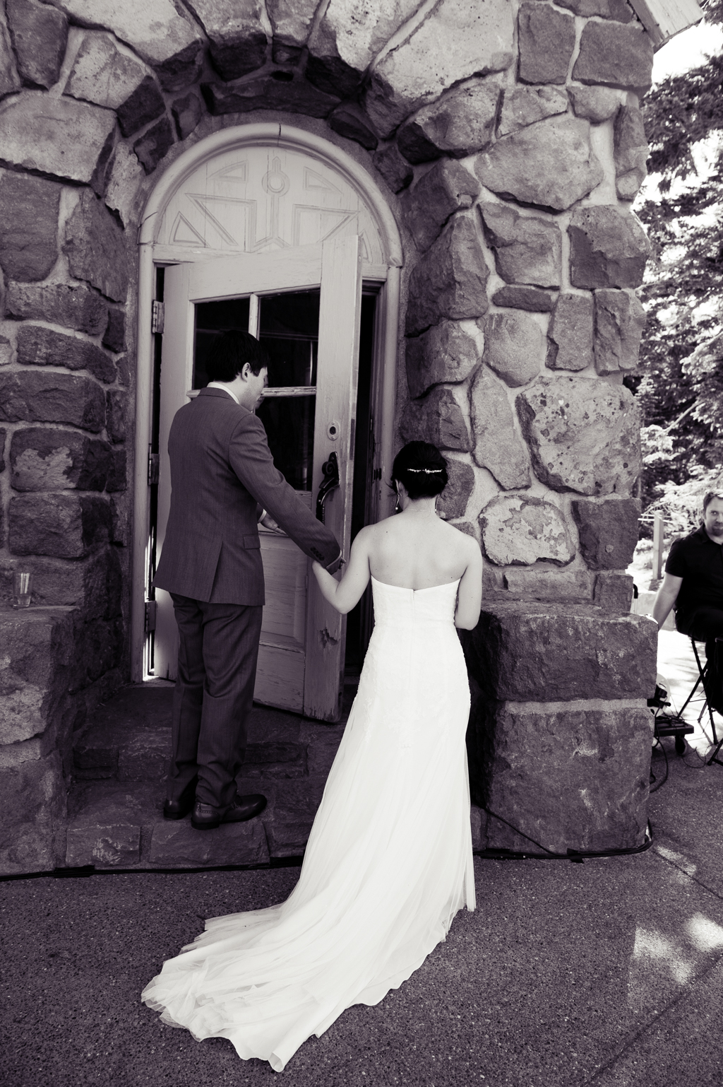 groom holds brides hand and opens the door to timberline lodge for her