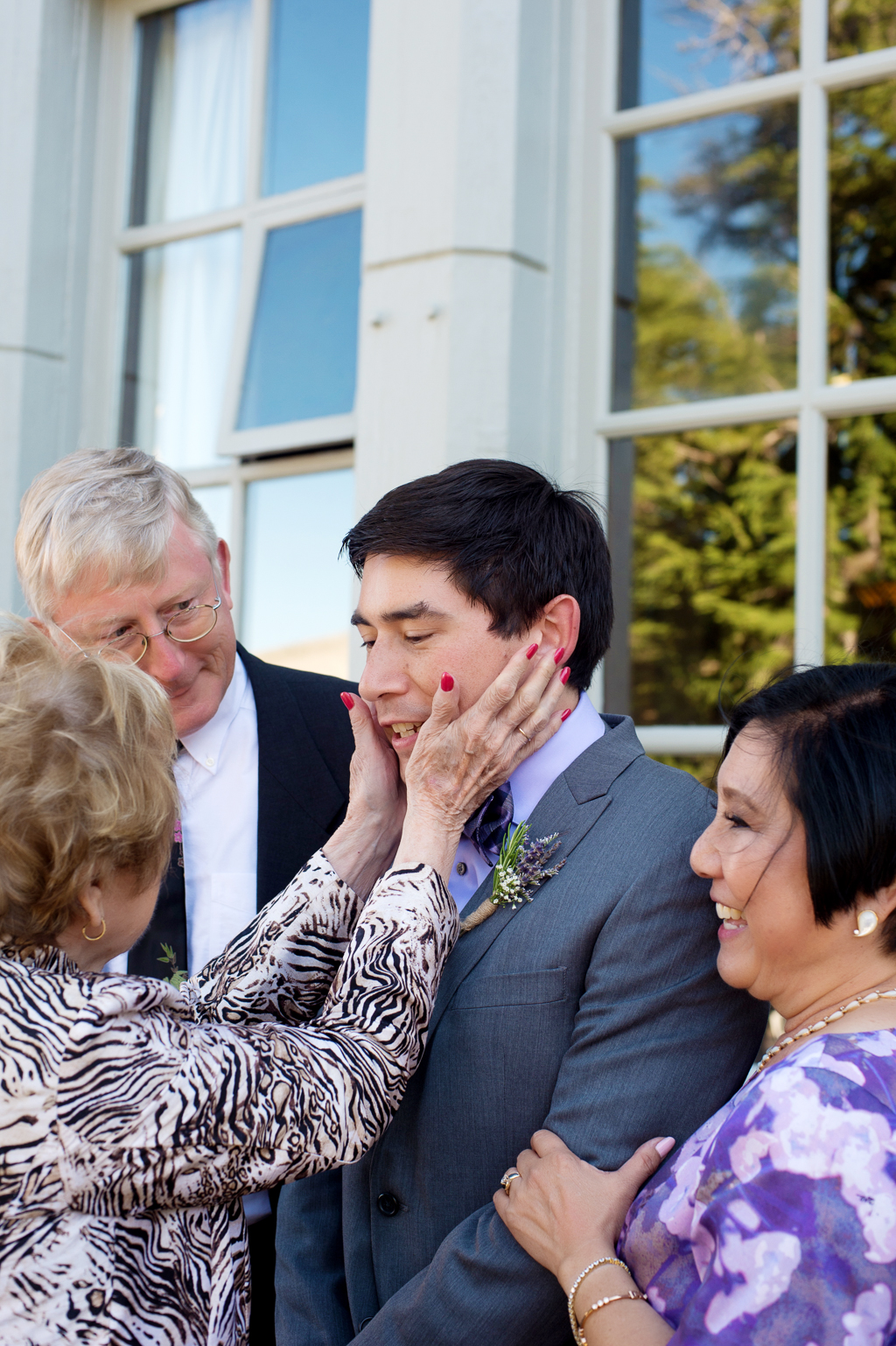a grandma puts her hands on groom's face