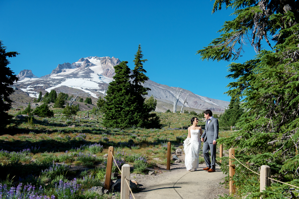 bride and groom walk on a path in front of mount hood at timberline lodge