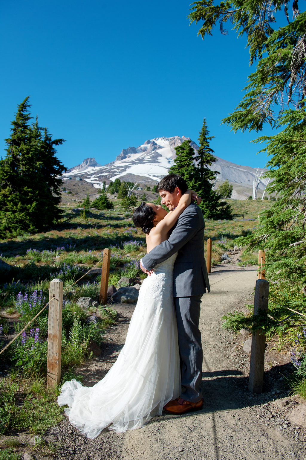 bride and groom kiss on a path in front of mount hood at timberline lodge