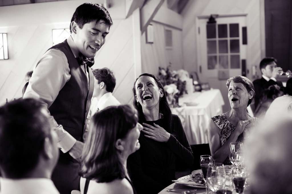 a wedding guest laughs heartily at the groom