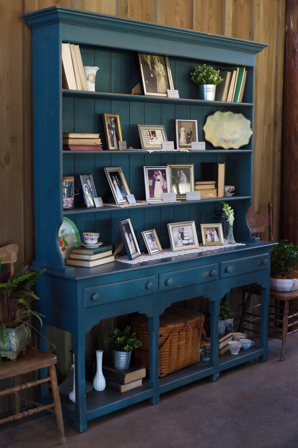 an old antique shelf painted blue holds old family photos in frames