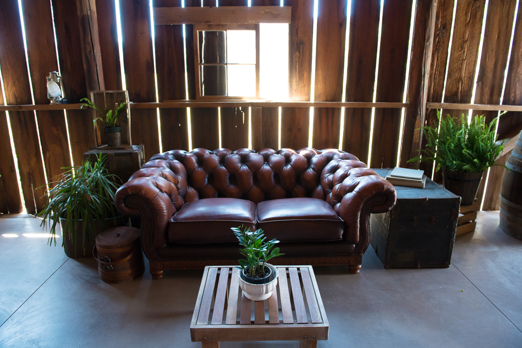 a large red leather tufted couch in the barn for wedding reception