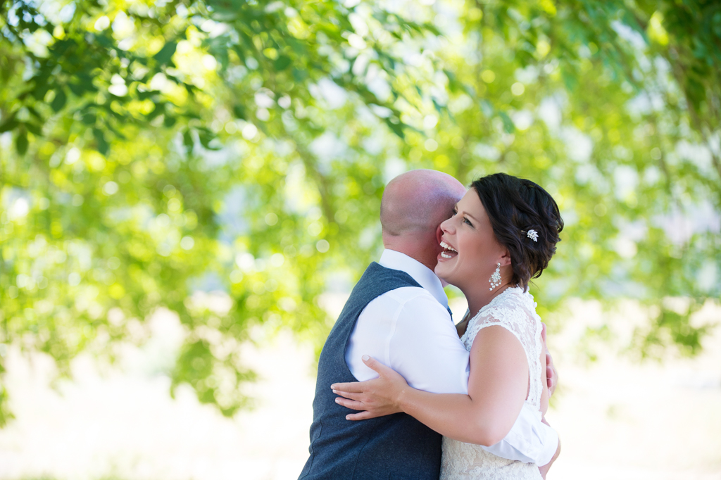 a bride laughs happily as her groom hugs her
