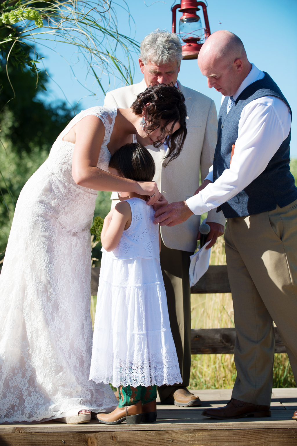 bride and groom give necklace to daughter during wedding ceremony