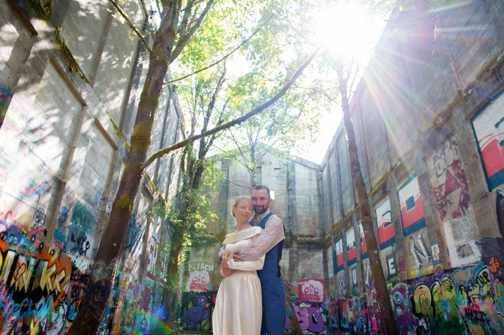 bride and groom stand in the middle of an old mill in vernonia that is covered in graffiti