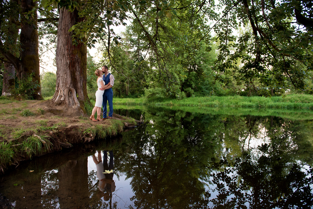 a bride and groom kiss on the bank of nehalem river at hawkins park