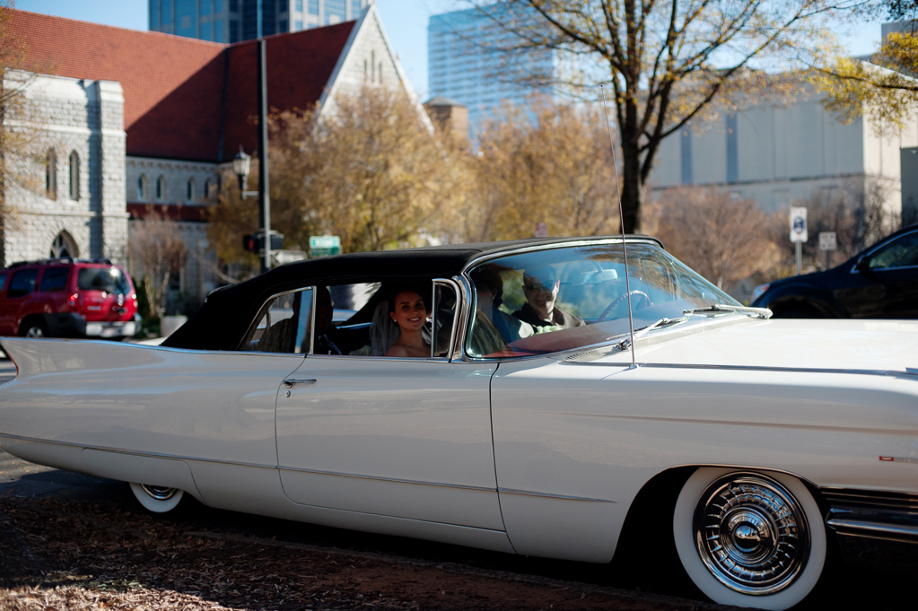 bride and groom arrive to ceremony in vintage white cadillac convertible