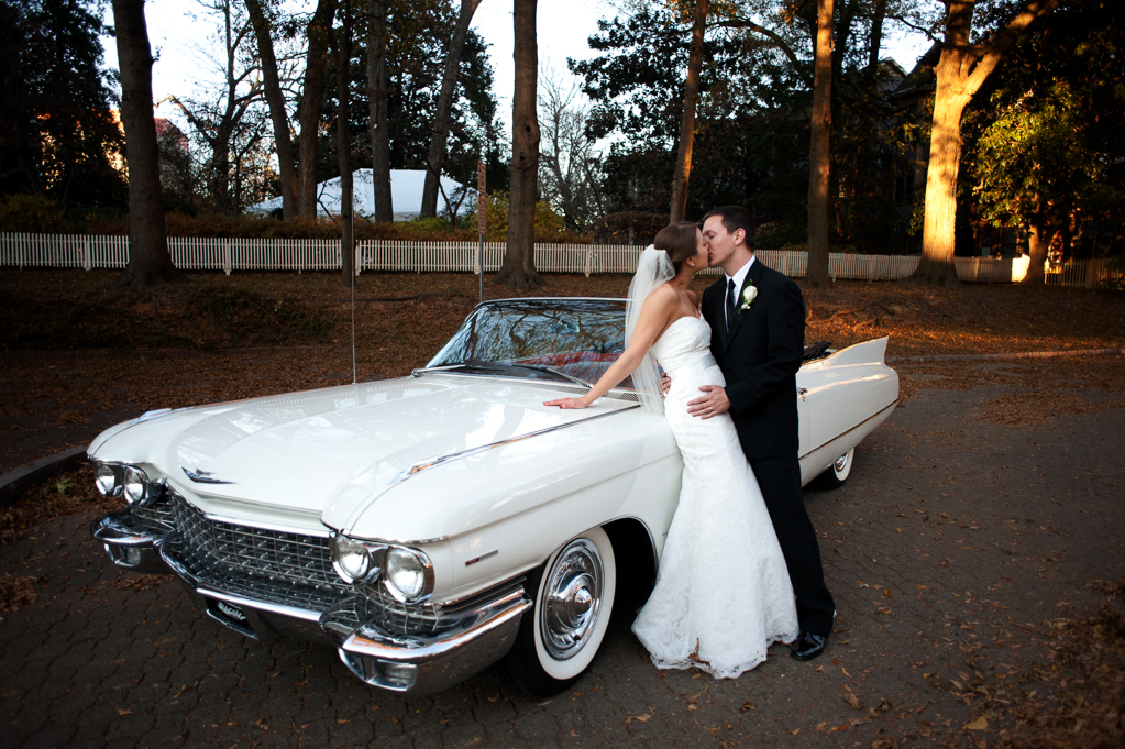 bride and groom lean against vintage white cadillac convertible and kiss
