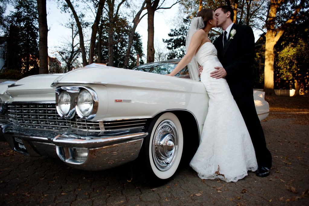 bride and groom lean against vintage white cadillac convertible and kiss