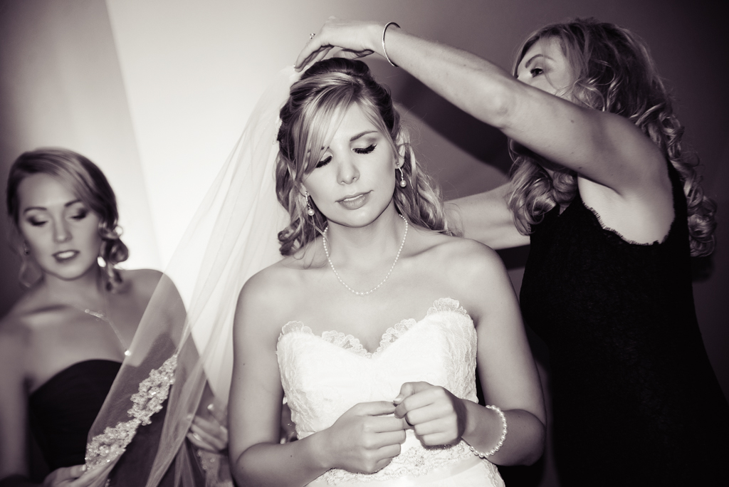 a mom and bridesmaid helps a bride into her veil