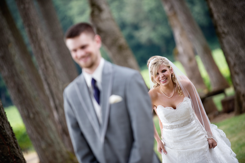 a bride laughs as she sneaks up behind her groom during their first look