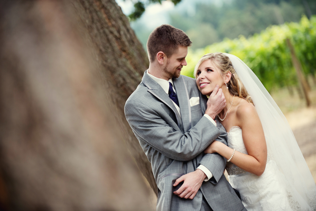 a groom looks at his bride and caresses her face as she smiles back at him