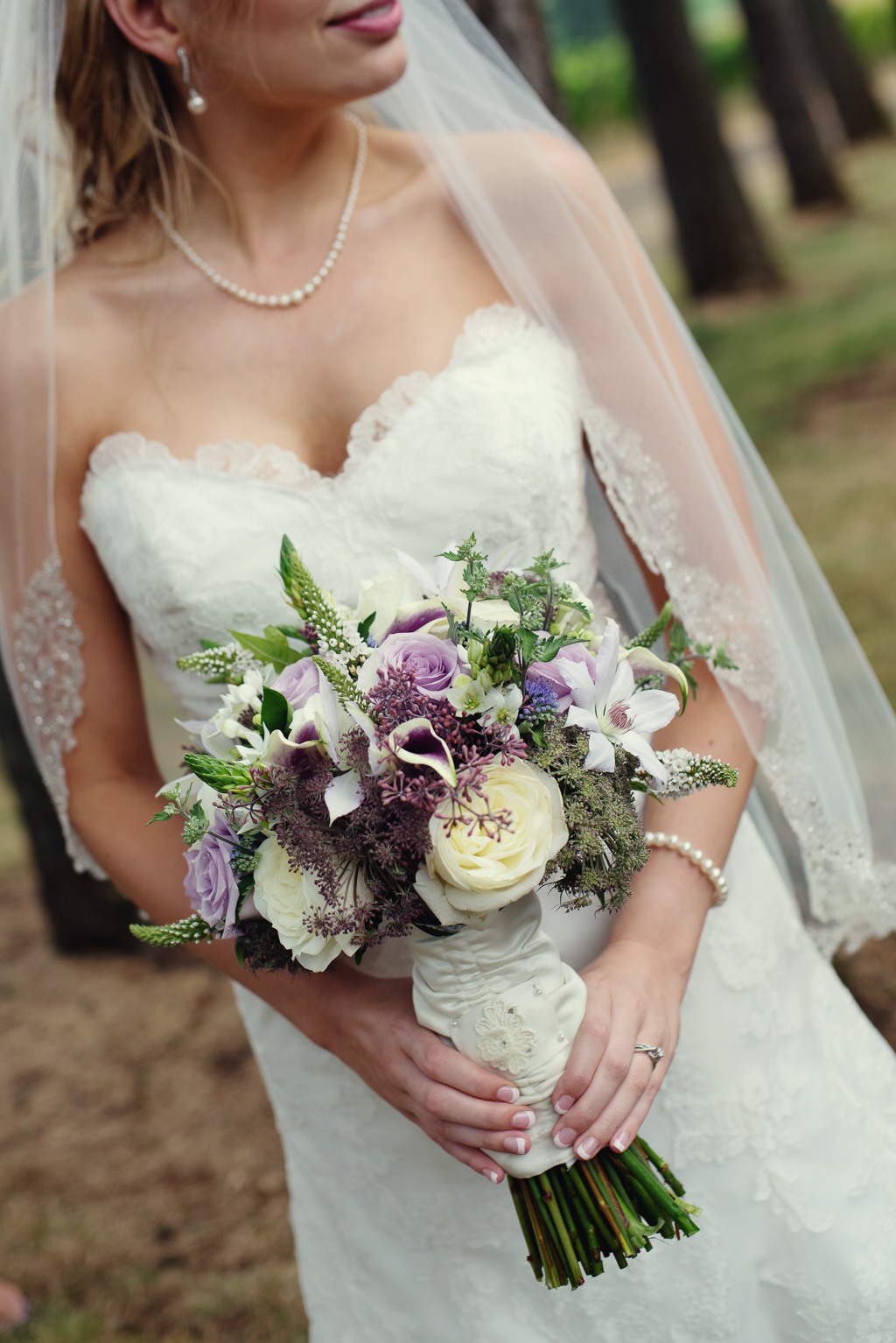 a bride holds her pretty lilac purple and ivory bouquet