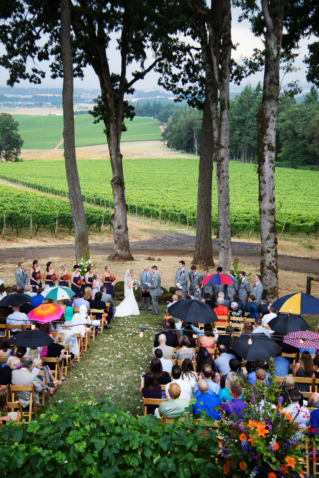 a rainy wedding ceremony under tall trees at vista hills overlooking the vineyard