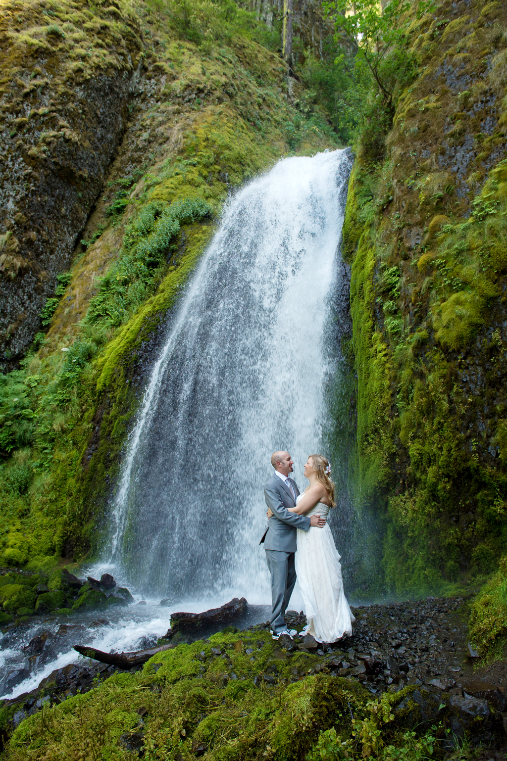 a newly married couple embrace in front of wahkeena falls