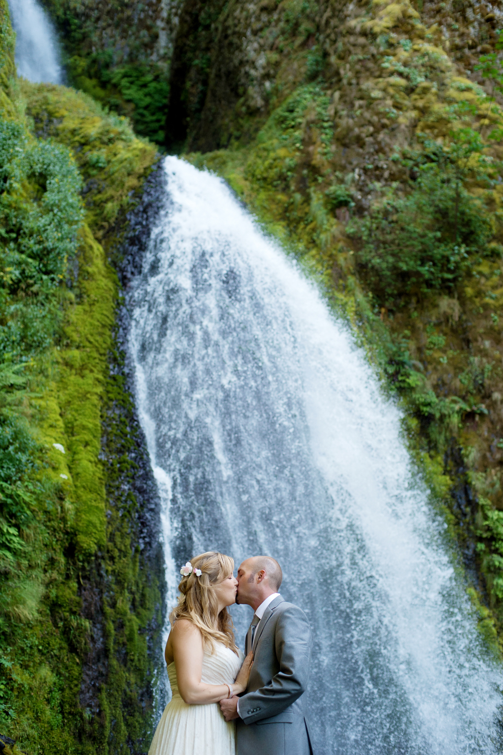 a bride and groom kiss with wahkeena falls in the background