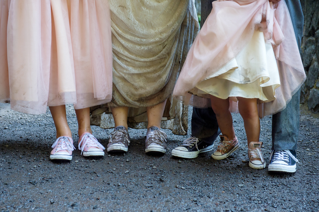 very muddy shoes after a wedding ceremony at wahkeena falls a bride wears white converse, a groom wears black converse, and two girls in pink dresses wear pink converse