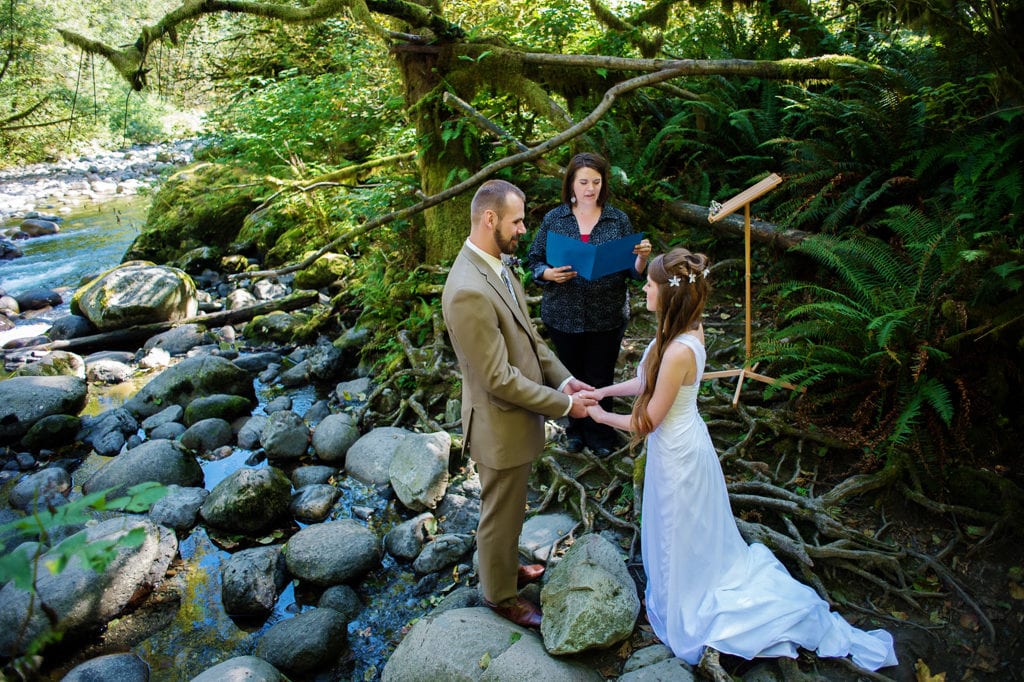 a bride and groom elope in the woods next to a stream