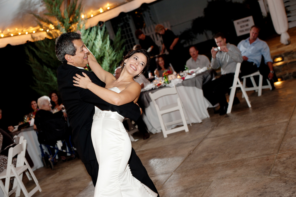 a father of the bride dips his daughter during their father daughter dance at the wedding reception