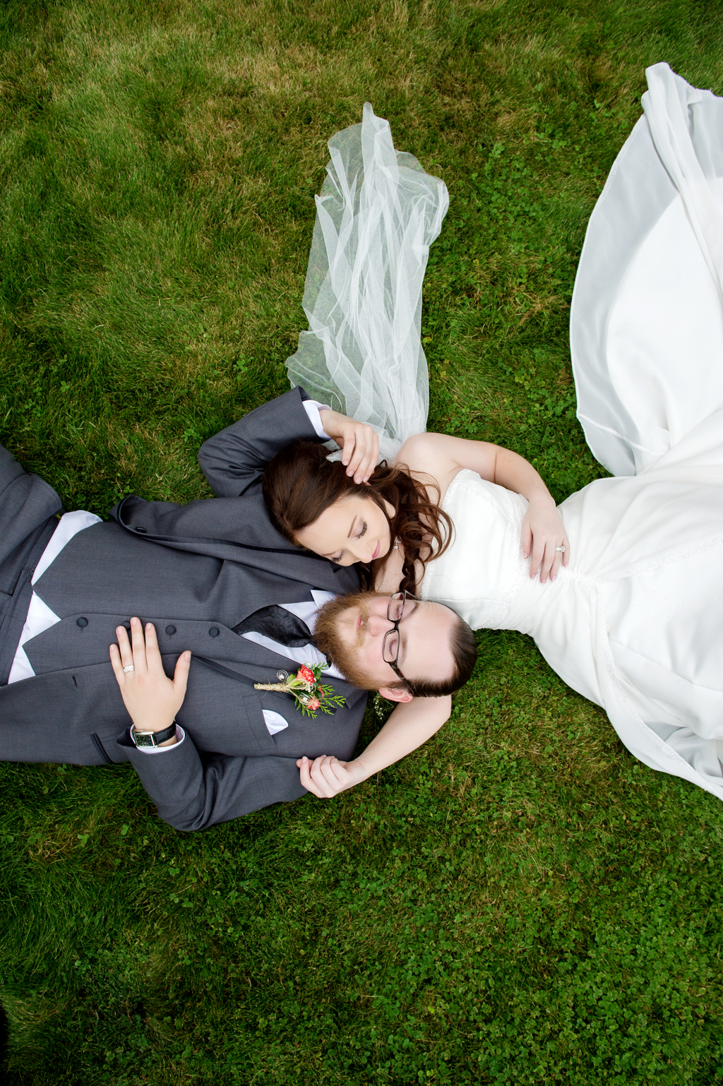 bride and groom lay head to head in grass