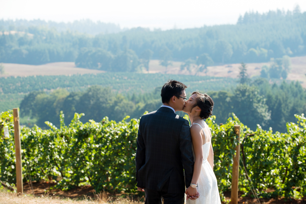 bride and groom kiss overlooking willamette valley vineyards