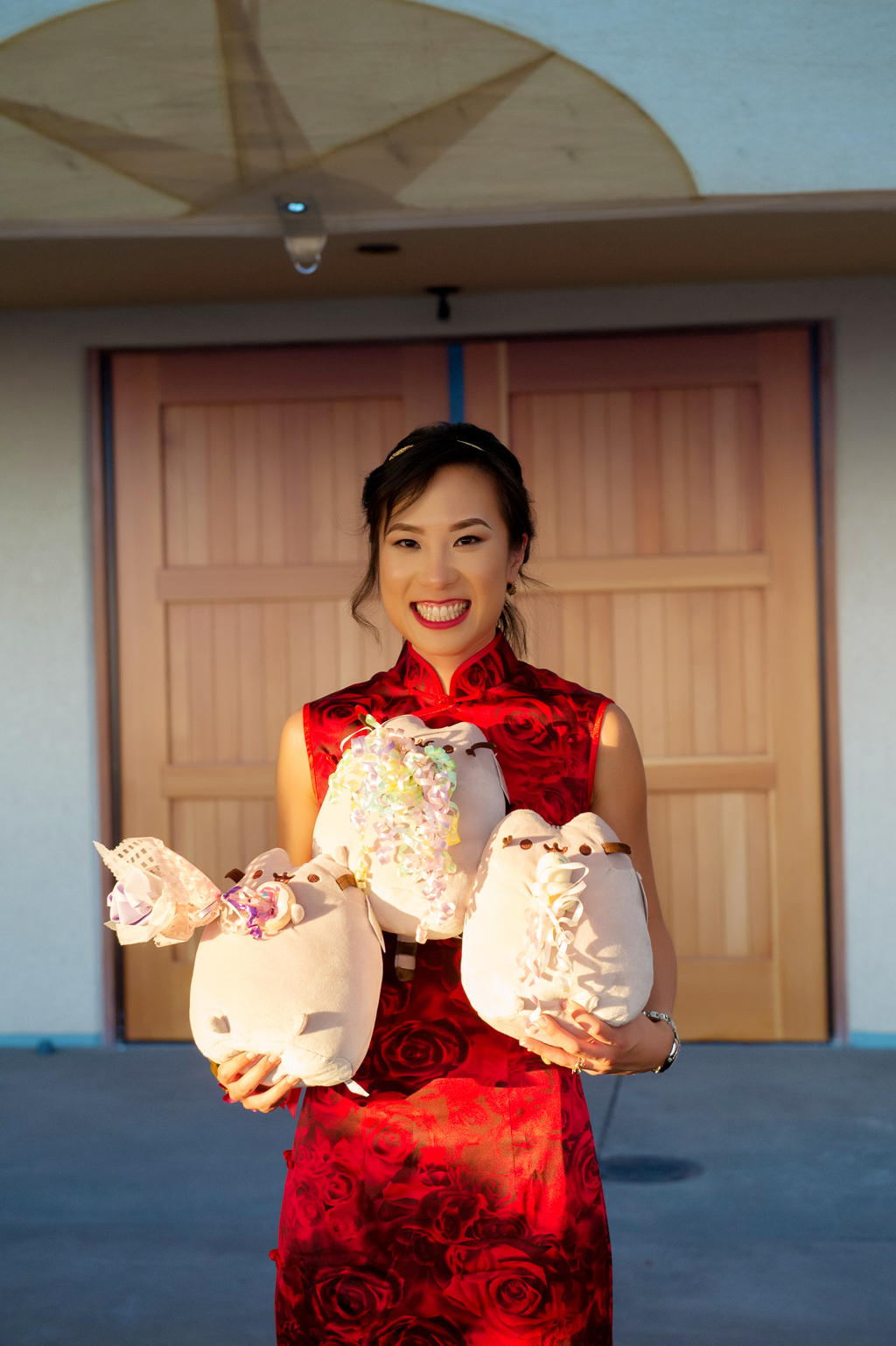 bride in red wedding dress holds 3 pusheen plushies