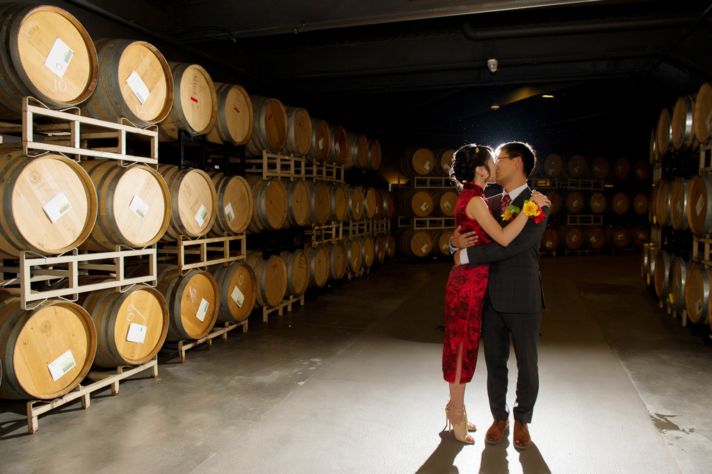 bride and groom embrace in the wine barrel room at willamette valley vineyards