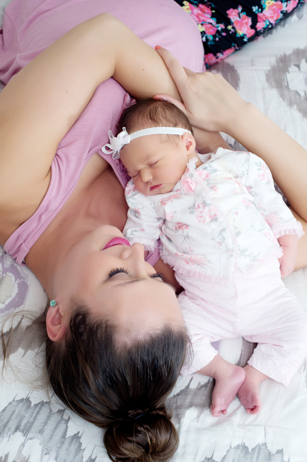 mom cuddles with newborn baby girl on bed