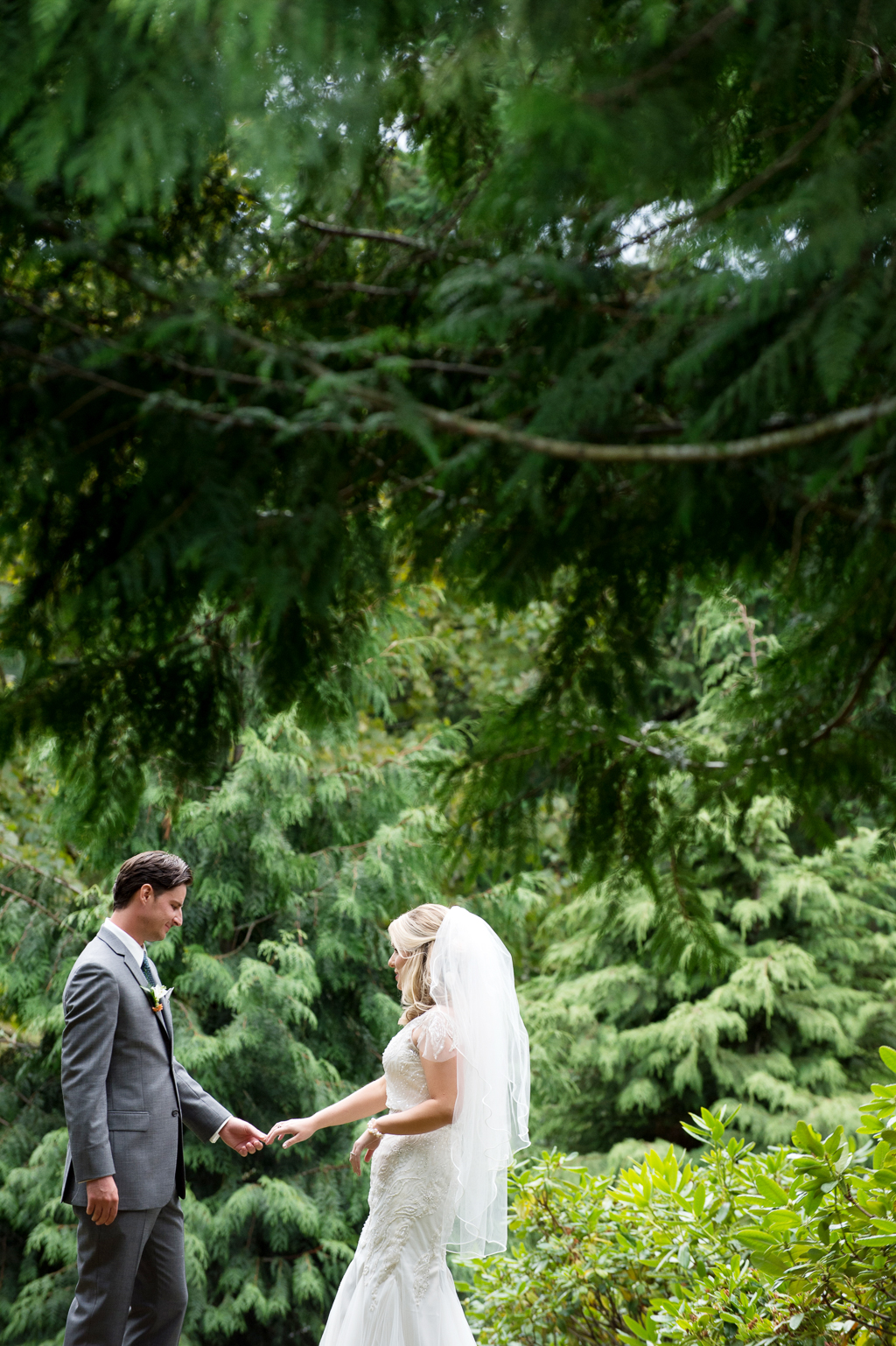 a bride and groom have first look under lush trees at world forestry center