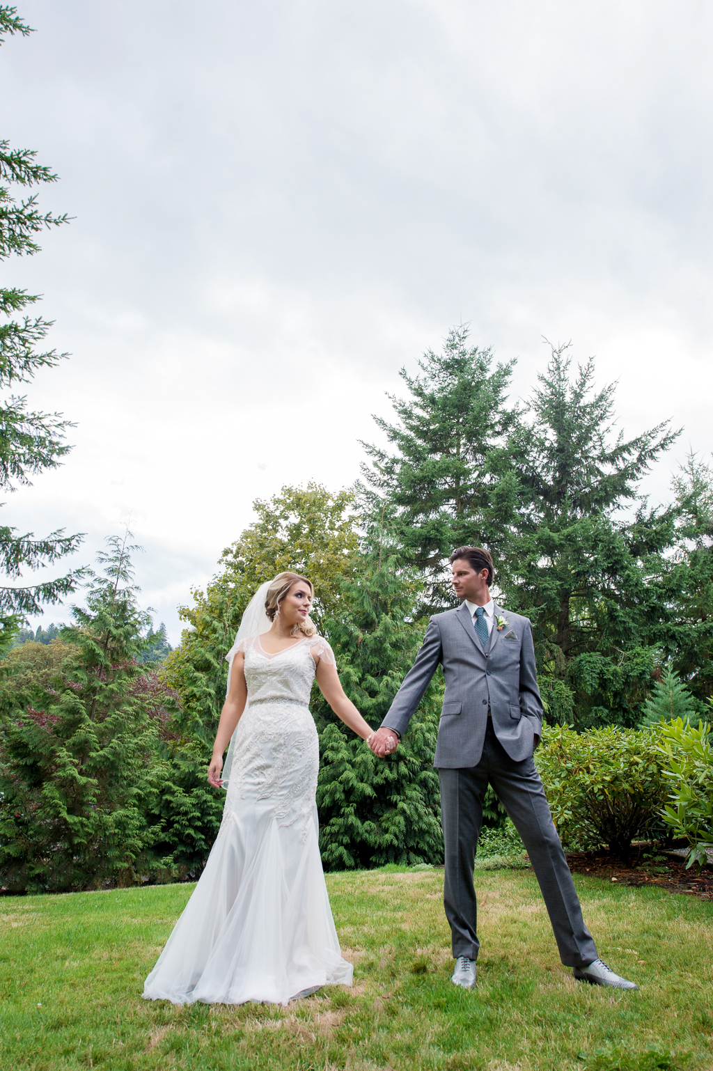 bride and groom hold hands under a big sky and trees