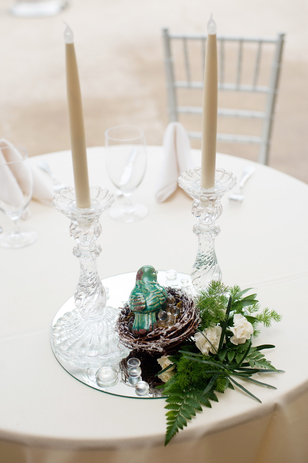 ferns and porcelain bird in a nest decorate a wedding reception table