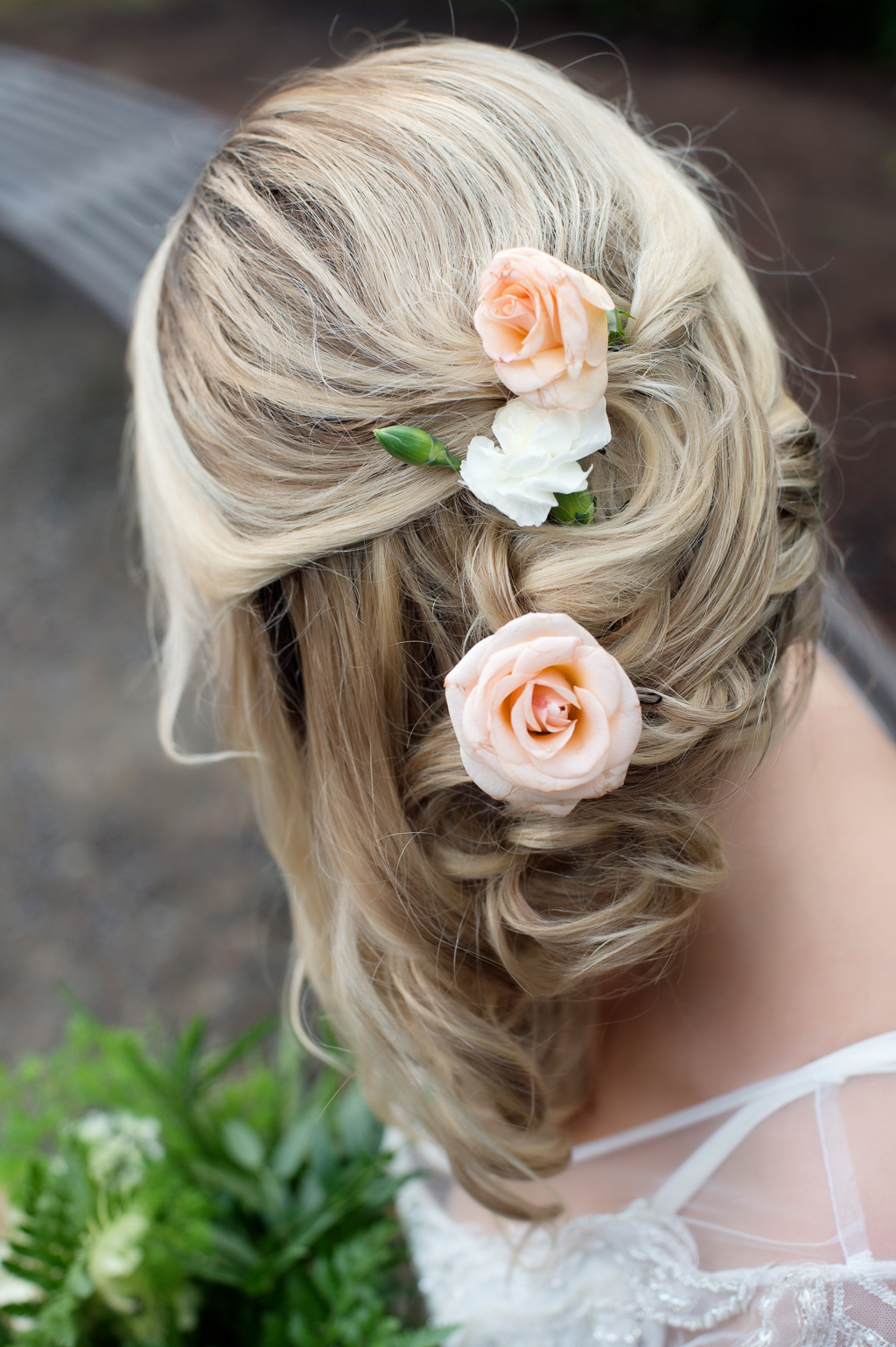 a bride has loose flowy wedding hair adorned with peach roses
