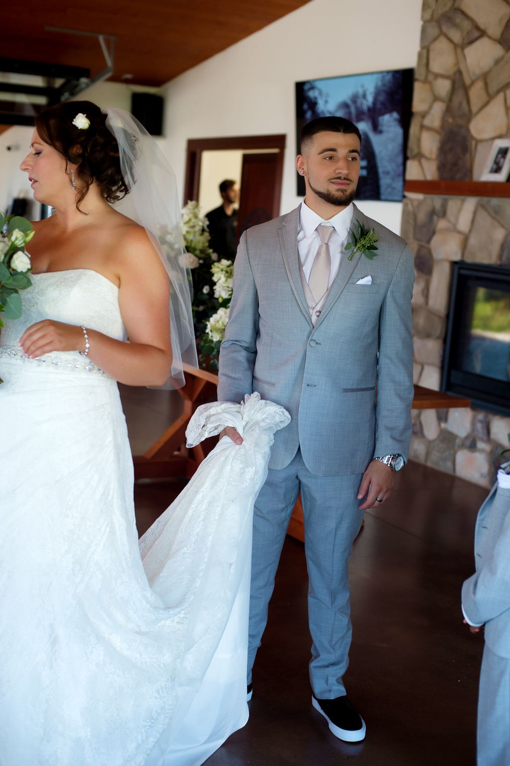 a groomsman holds the brides wedding dress