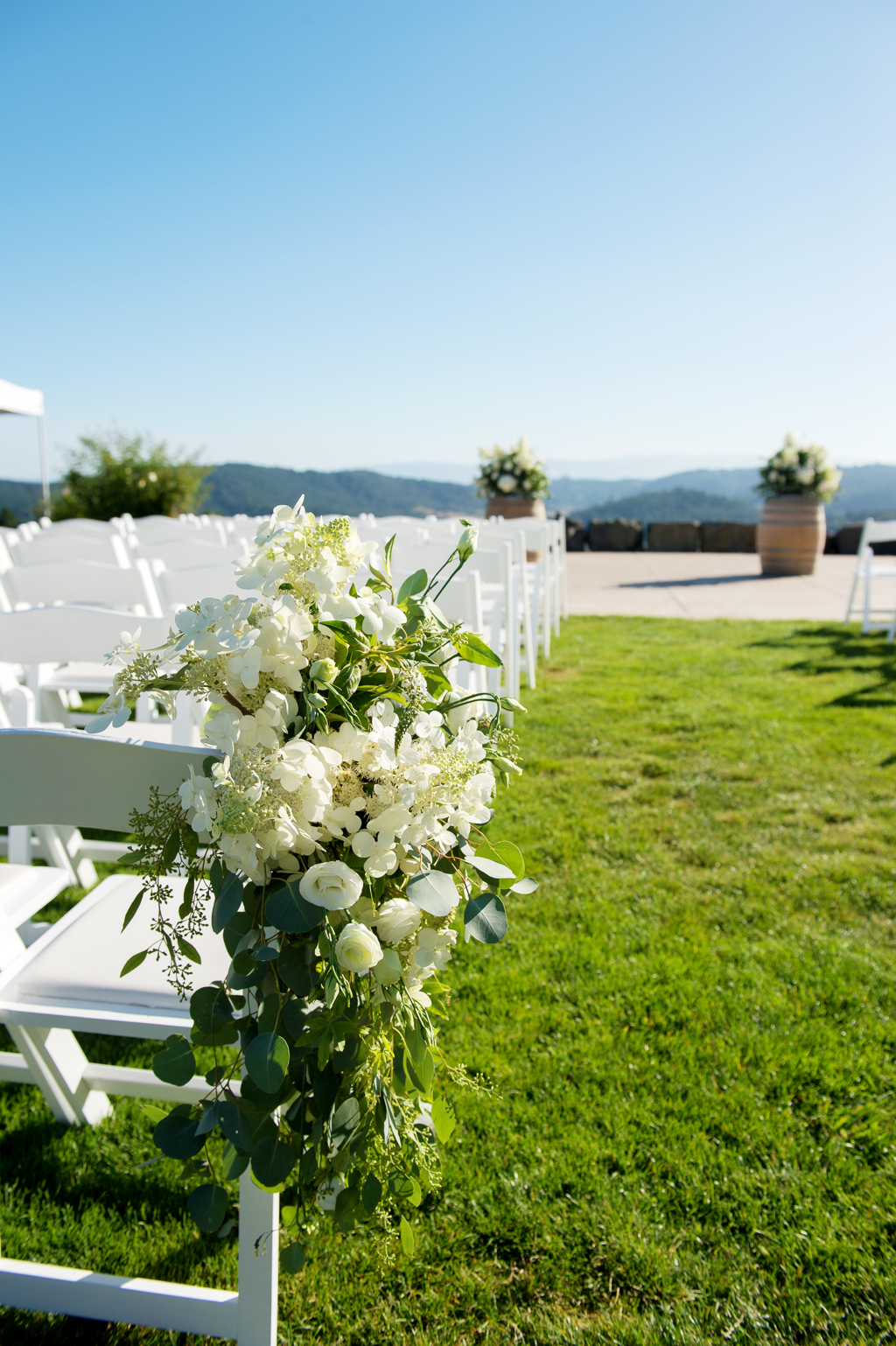 large bouquets of ivory and green flowers adorn the wedding chairs 