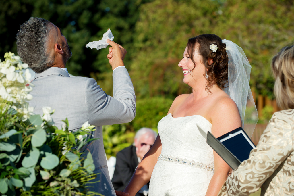 the groom holds a downy dryer sheet in the air to try to keep bumble bees away during wedding ceremony