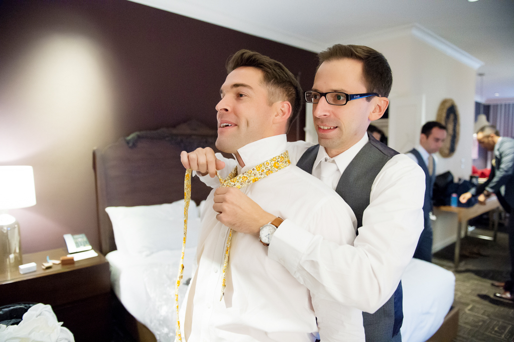 groom helps his best man tie his wedding tie
