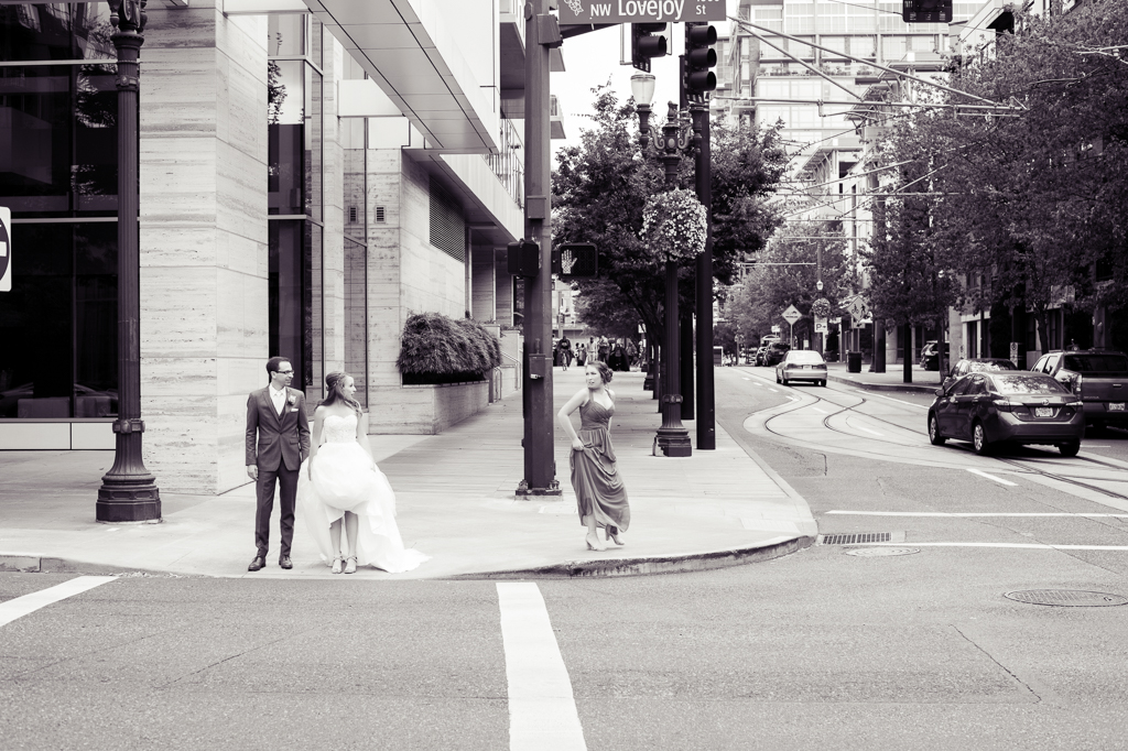 bride and groom stand on a street corner in nw portland waiting to cross