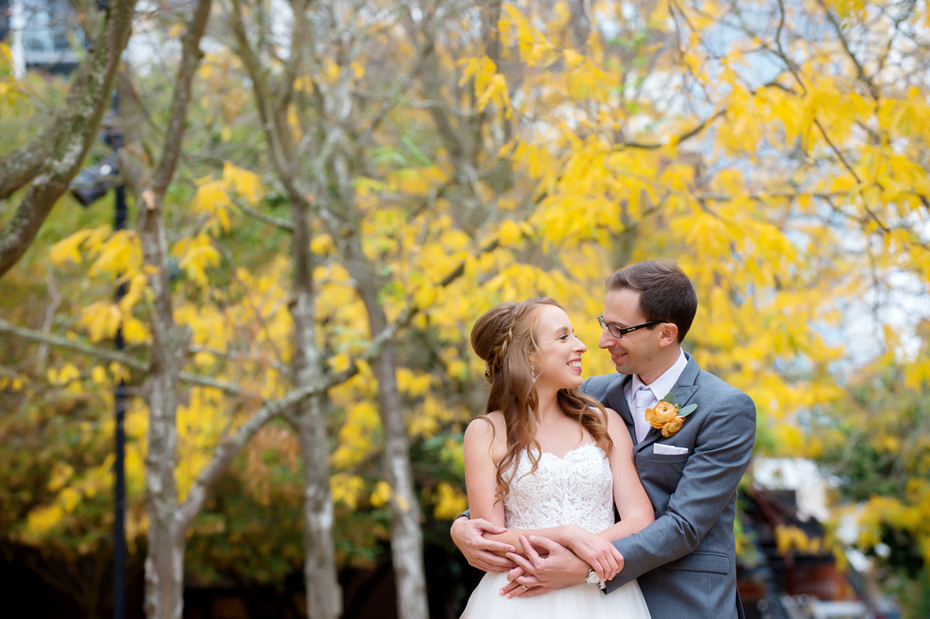bride and groom embrace under a tree of yellow leaves