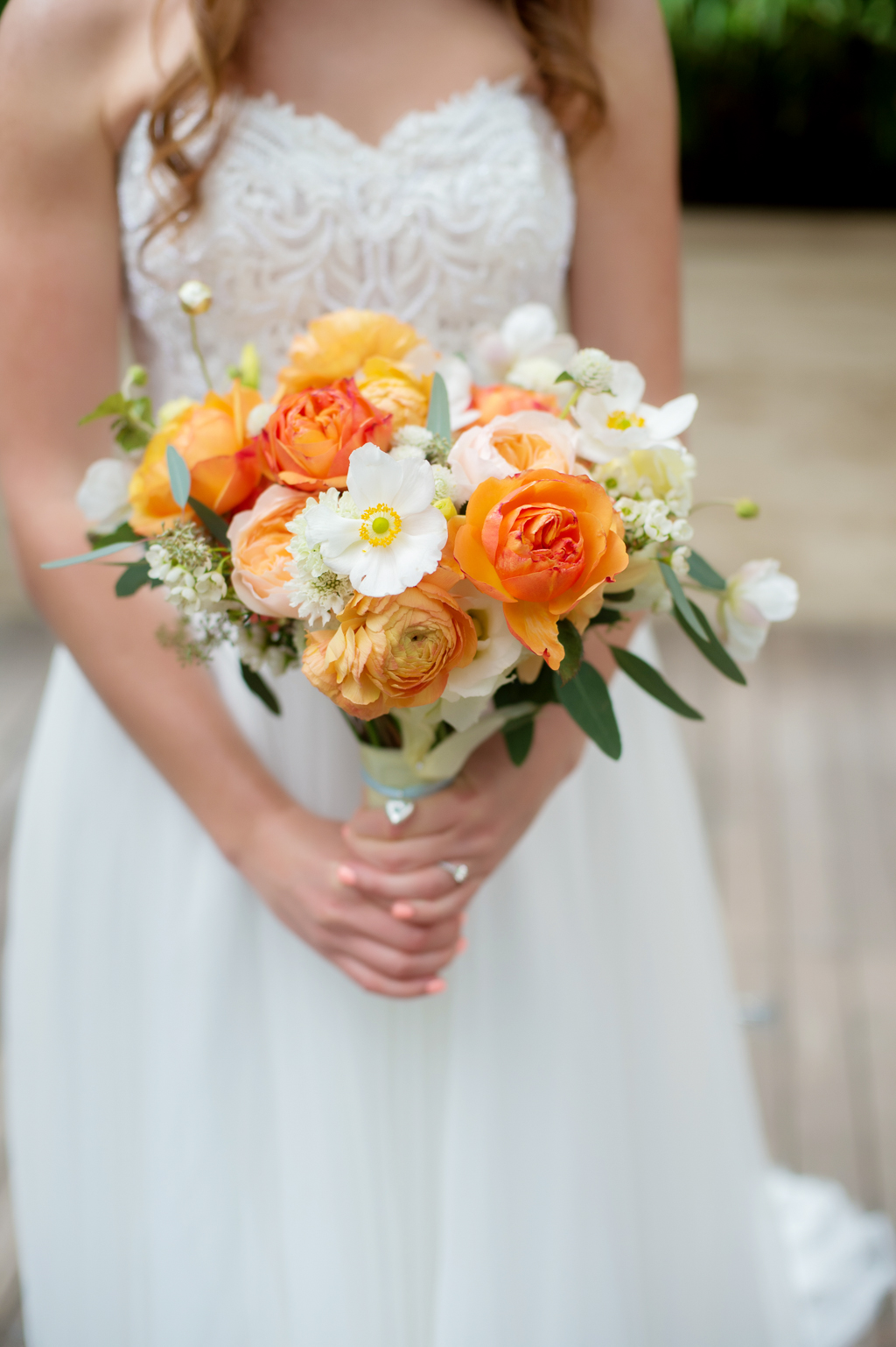 bride holds pretty ivory peach and orange bouquet