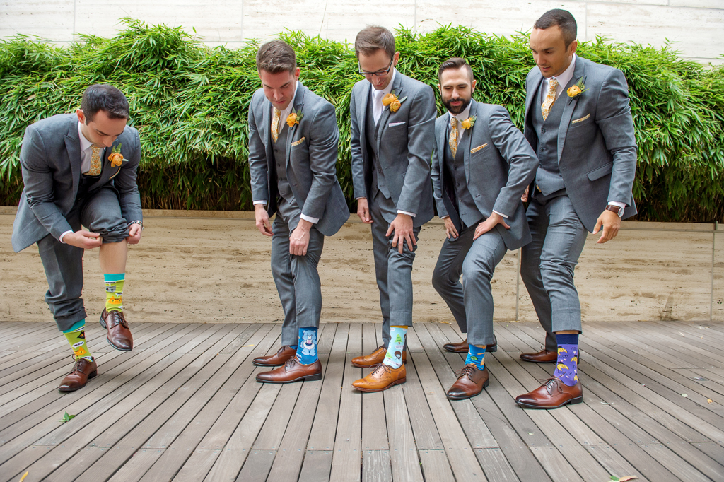 groomsmen lift their pants to show off their happy feet socks