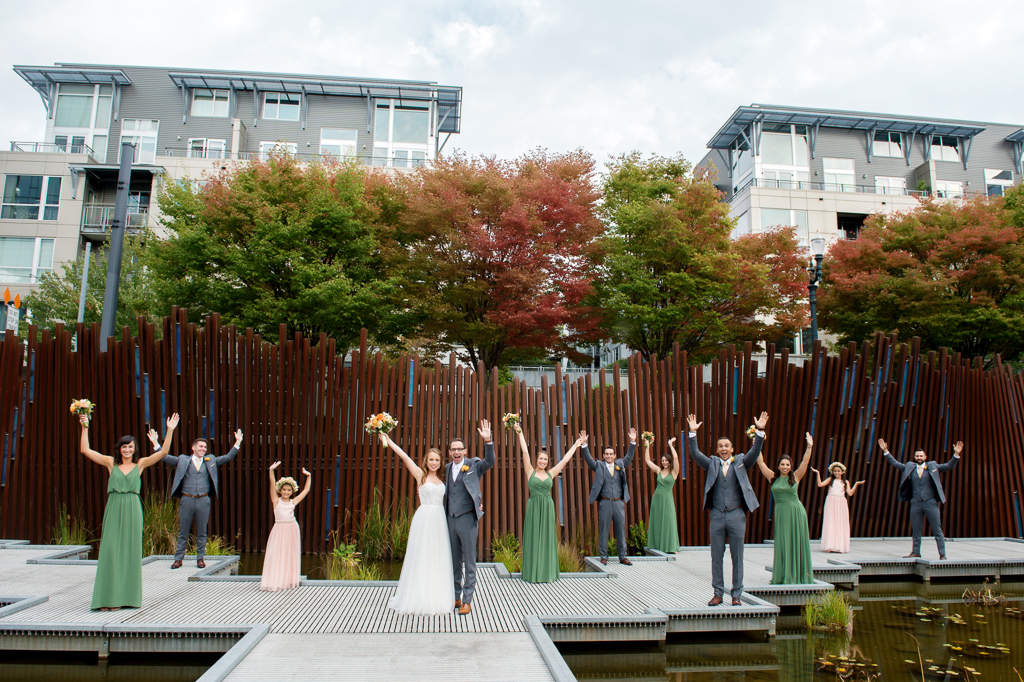 bridesmaids in green dresses and groomsmen line the boardwalk at tanner springs park