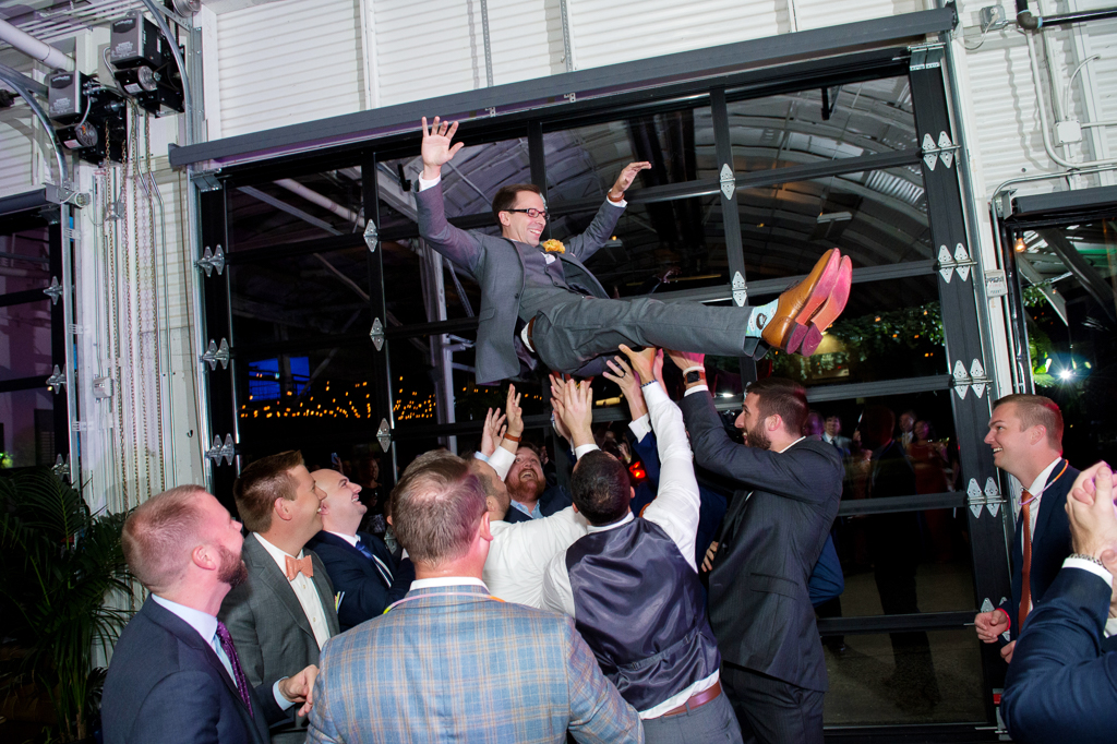 groomsmen toss a groom in the air above their heads at a wedding reception