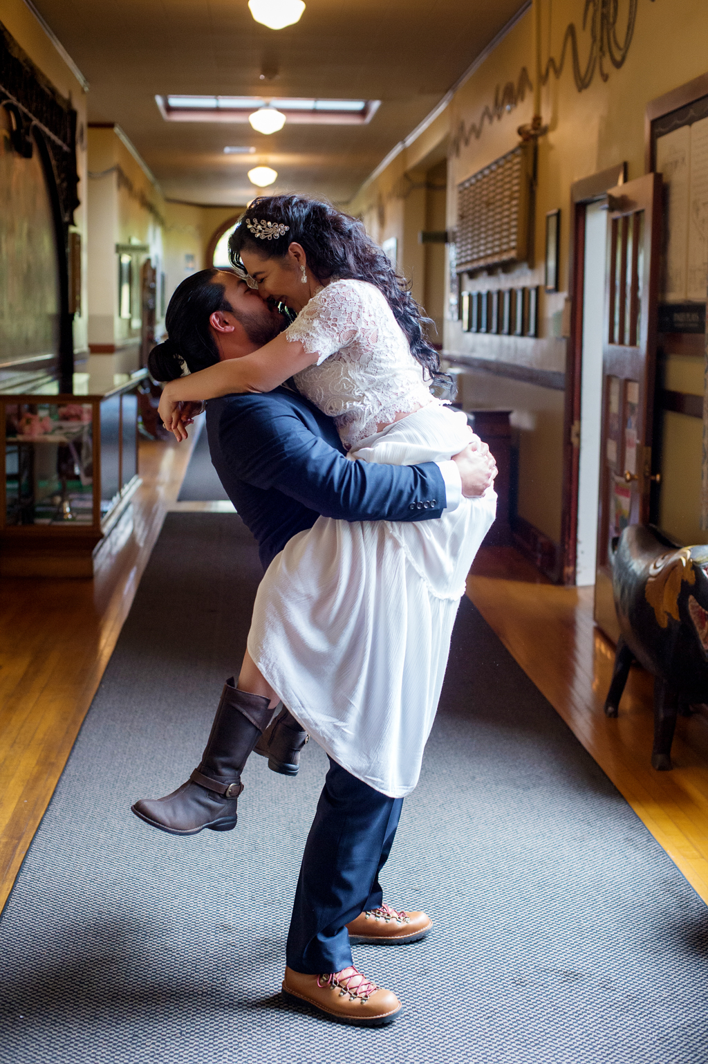 a bride jumps into a groom's arms in the hallway of mcmenamins kennedy school