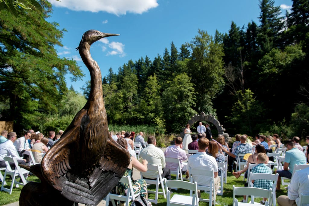 a bronze bird sculpture looks over the  wedding ceremony at caswell sculpture garden