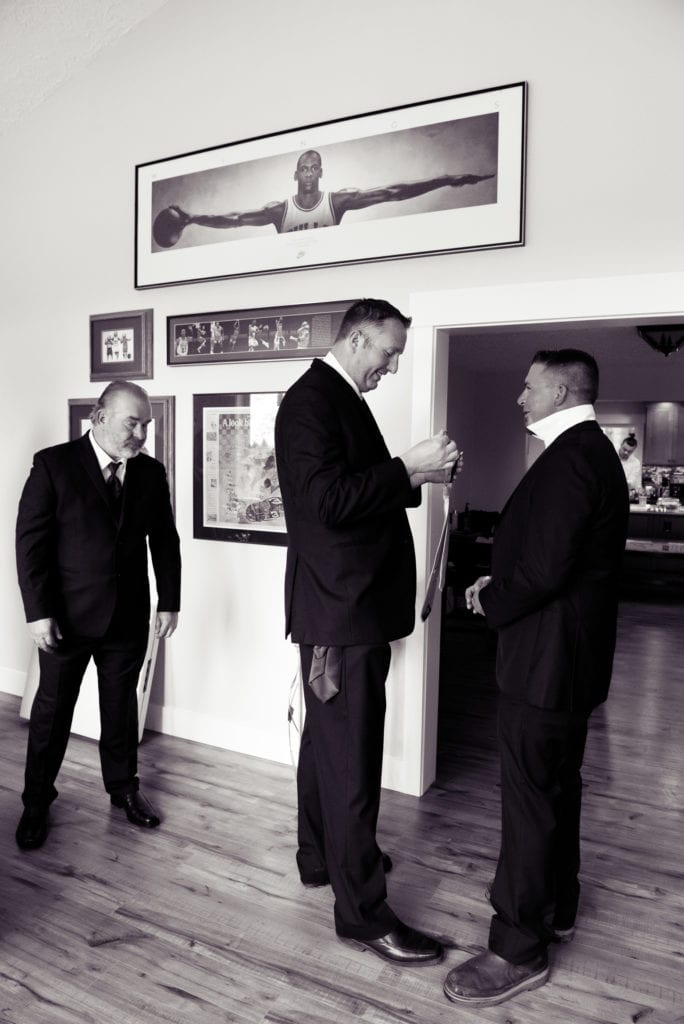 tall best man helps groom with tie underneath a large portrait of michael jordan