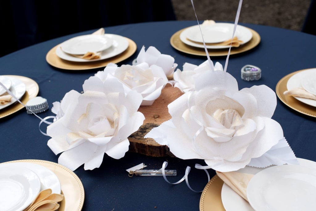 large white paper flowers are used as centerpieces for a wedding reception
