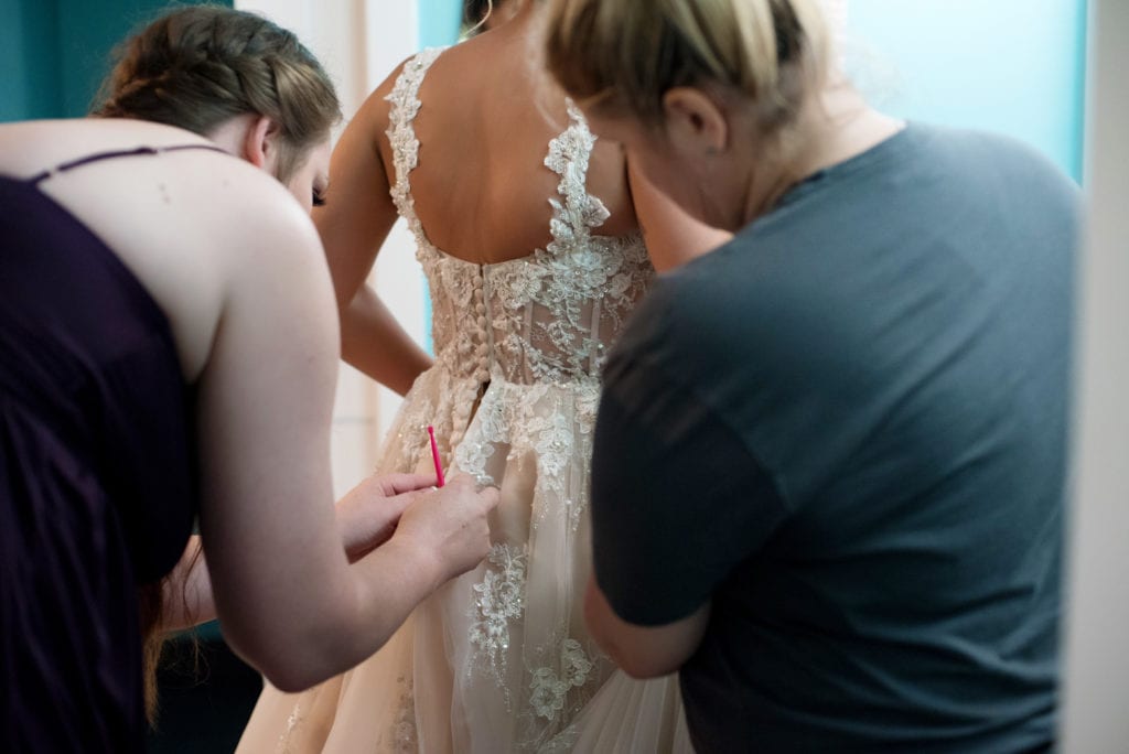 helping bride into her wedding dress
