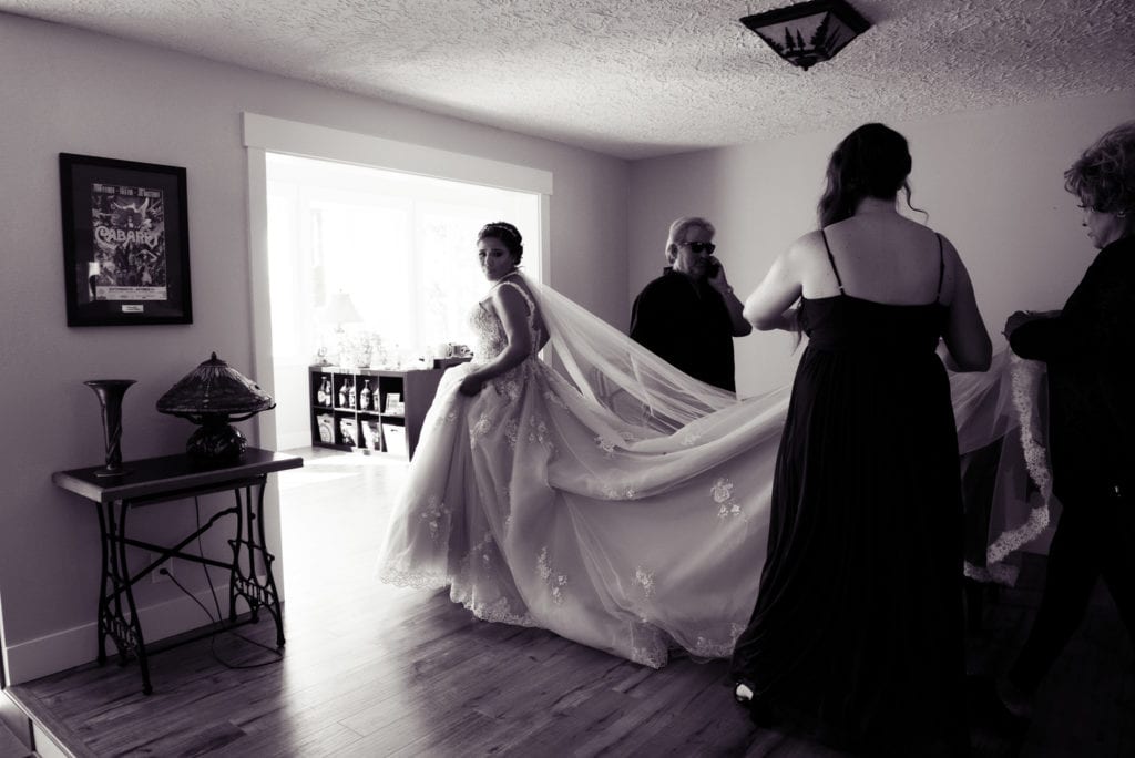 a bride with a very long dress train and veil walks into a brightly lit room