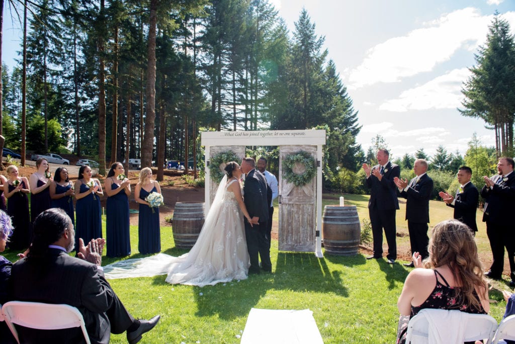 the bride and groom have their first kiss during their brush prairie backyard wedding
